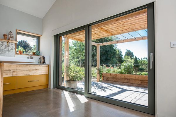 Sunlit bathroom with large sliding glass doors opening to a wooden pergola and garden.