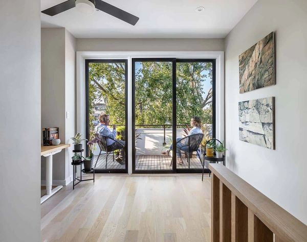 Two people sitting on a balcony surrounded by plants and art.