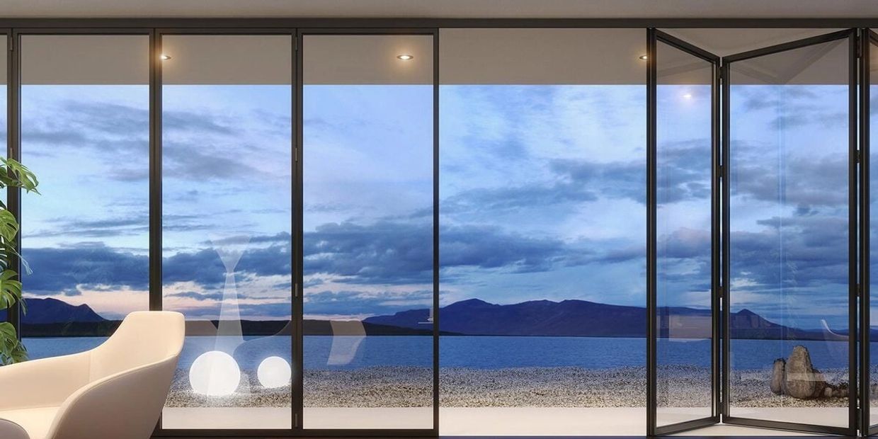 Modern living room with large glass doors overlooking a serene lake and mountains.