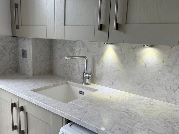 Modern kitchen countertop with marble surface and built-in sink under cabinet lighting.