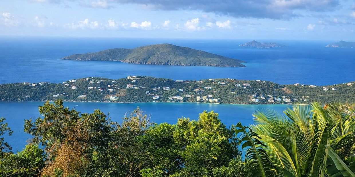 Scenic view of lush islands surrounded by clear blue ocean under a partly cloudy sky.