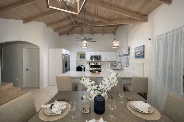 Modern kitchen and dining area with wooden vaulted ceiling and neutral decor.