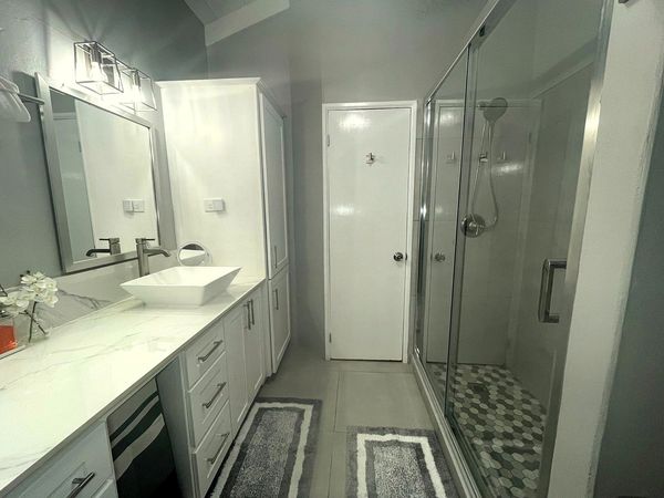 Modern bathroom with white cabinetry and glass shower enclosure.