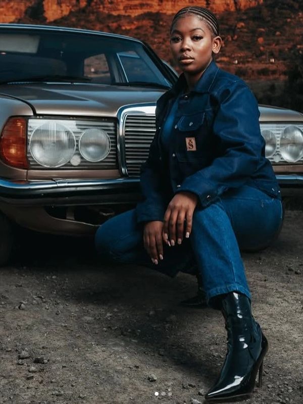 Woman posing in front of a vintage car.