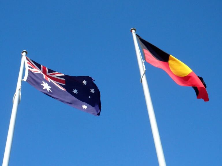 Side by side flying in the wind, the flags of the commonwealth of Australia and the first australian