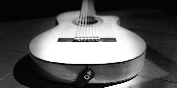 Close-up of an acoustic guitar lying on a wooden surface in black and white.
