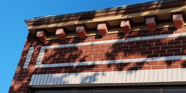 Close-up of a decorative brick building facade with blue sky.