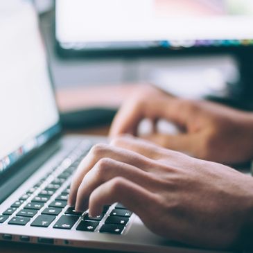 Close-up of hands typing on a laptop keyboard.