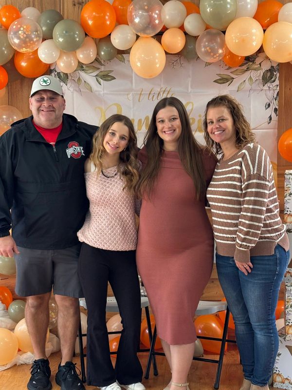 Family smiling together at a pumpkin-themed party with festive balloons.