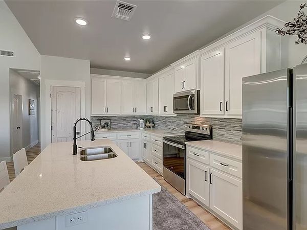 Modern kitchen with white cabinets and stainless steel appliances.