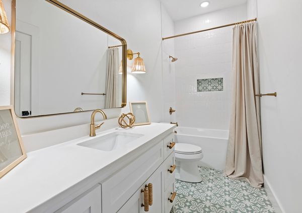 Elegant white bathroom with gold accents and patterned floor tiles.