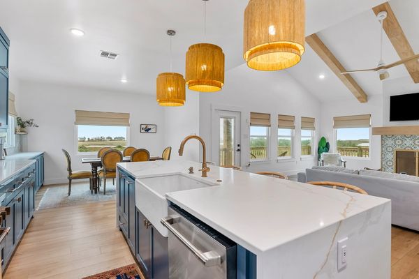 Modern kitchen with white marble island and wooden pendant lights.