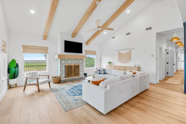 Bright living room with vaulted ceiling, wood beams, and a cozy fireplace.