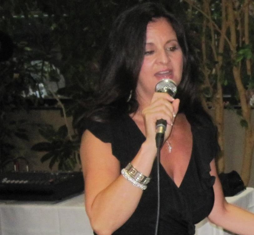 Woman singing into a microphone at an indoor event.