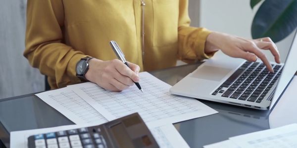 Person working on financial documents with a laptop and calculator.