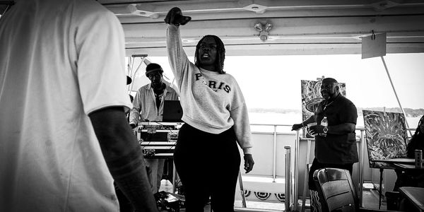A woman raises her fist in a powerful gesture during a gathering on a boat.