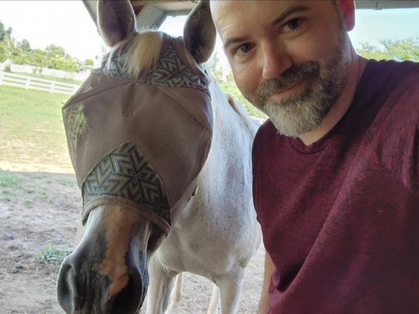 A team member taking a photo with a horse.