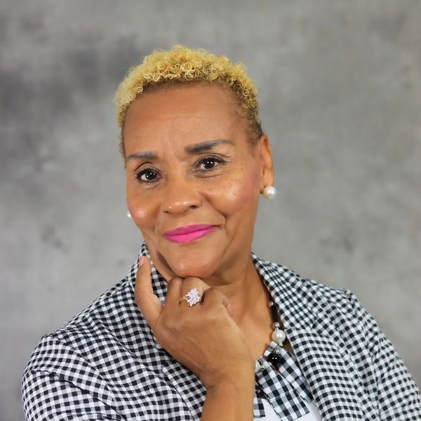 Confident woman with short blonde curls and bright lipstick poses thoughtfully.