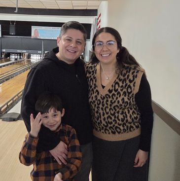 Family smiling together at a bowling alley.