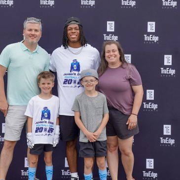 Family posing with a young athlete at a sports event.