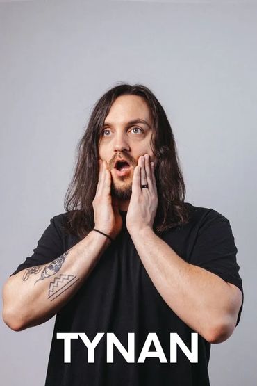 Man with long hair and tattoos expressing surprise.
