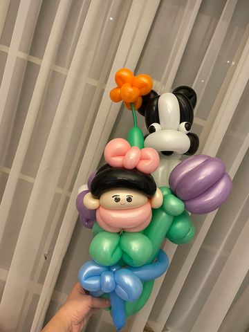 Colorful balloon sculpture of a girl holding flowers and a dog.