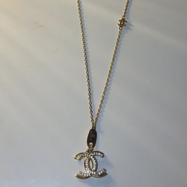 Gold Chanel necklace with pendant on white background.