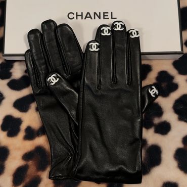 Black leather Chanel gloves with white logo accents on fingertips.