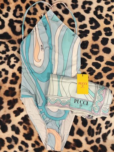 Stylish Pucci swimsuit with matching cover-up in pastel swirls, laid on leopard print fabric.
