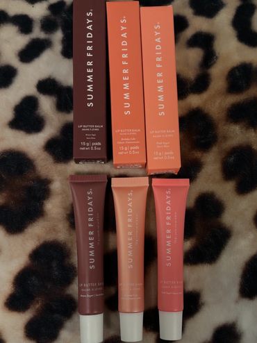 Three Summer Fridays lip butter balms in their boxes on a leopard print surface.