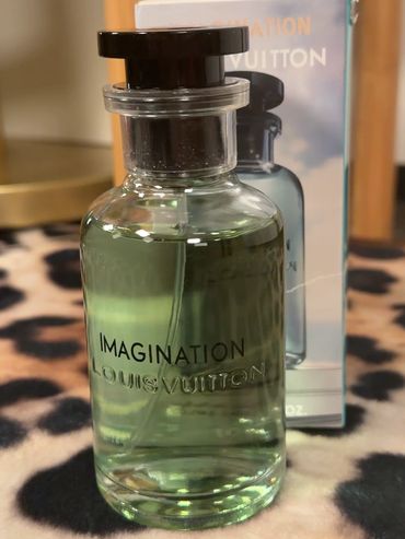 A bottle of Louis Vuitton Imagination perfume with its packaging in the background.