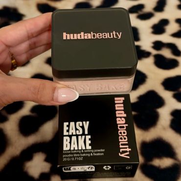 Huda Beauty Easy Bake loose baking and setting powder held over its box.