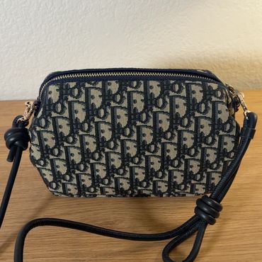 Designer patterned crossbody bag with black strap.