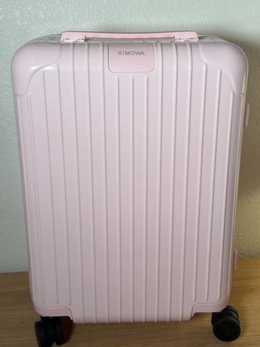 Pink Rimowa suitcase with wheels.