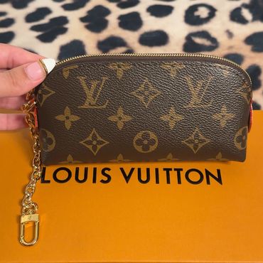 Louis Vuitton monogram key pouch with gold chain on branded box.