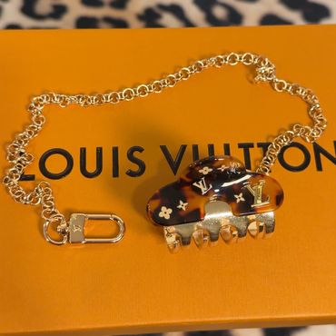 Gold chain bracelet with Louis Vuitton hair clip on branded box.