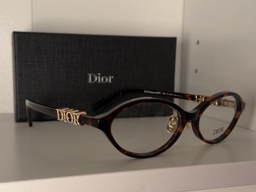 Dior eyeglasses with gold detailing and branded box.