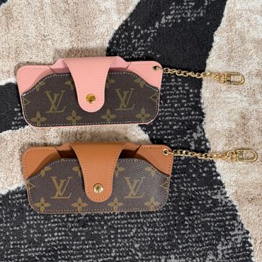 Two designer phone case pouches with Louis Vuitton logo.