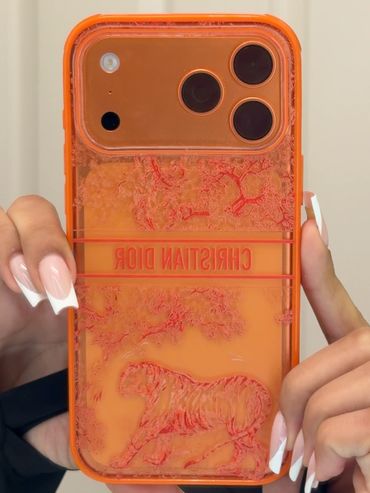 Orange Christian Dior phone case with tiger design on an iPhone.