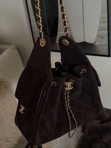 Elegant black Chanel handbag with gold chain details.