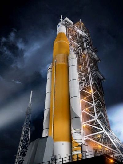 A large rocket on a launch pad at night, illuminated by lights.