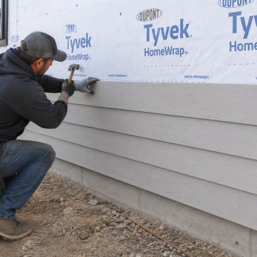Man installing siding on a house wall.