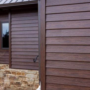 Close-up of brown house siding and stone foundation.
