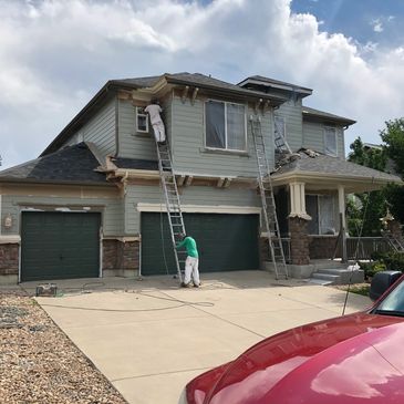 Two painters working on a two-story house exterior.