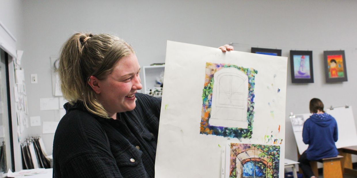 This is an image of a student holding up her colorful work-in-progress painting of a window.