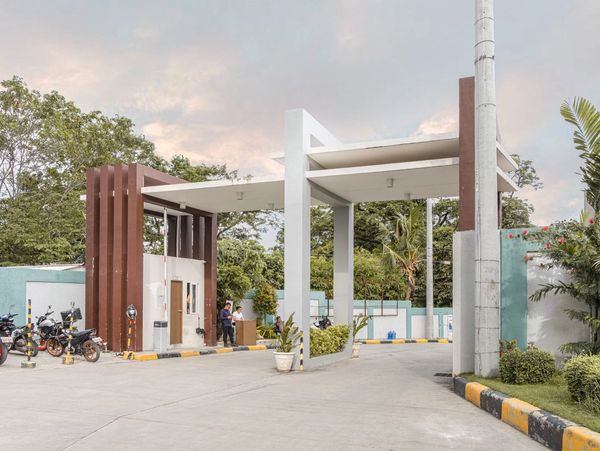 Modern gated entrance with security personnel and parked motorcycles.