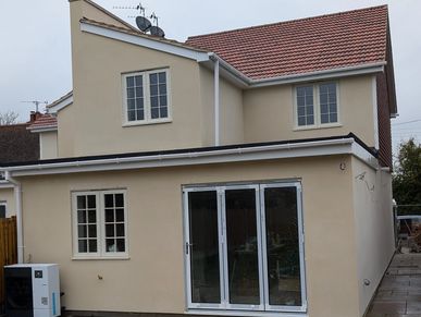 Modern two-story house with cream exterior and large glass doors.