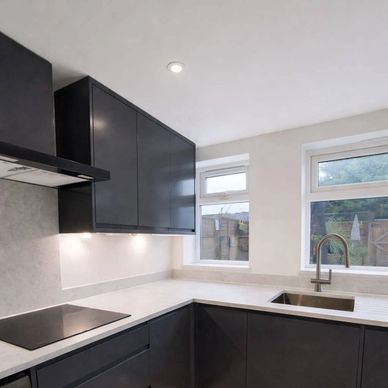Modern kitchen with black cabinets and white countertops.