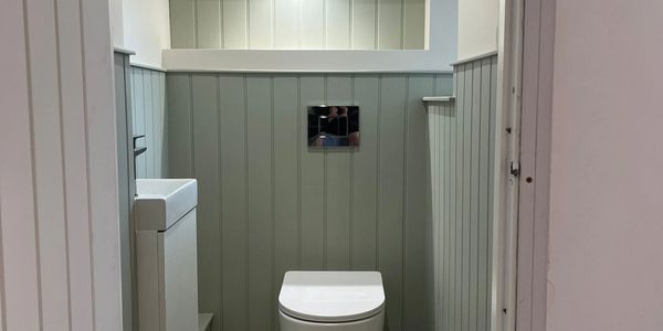 Compact bathroom with gray paneled walls and white toilet.