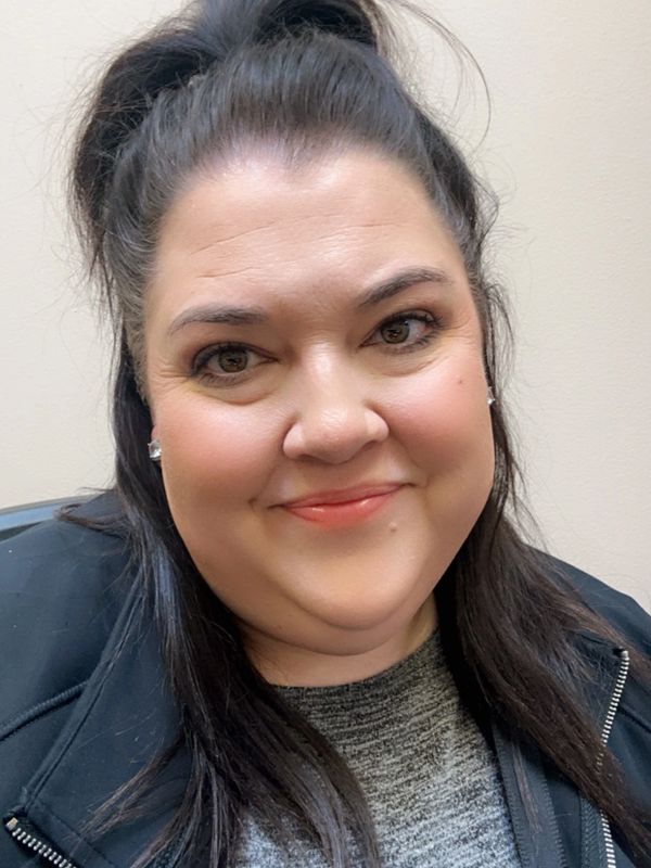 Close-up of a smiling woman with long dark hair and a black jacket.